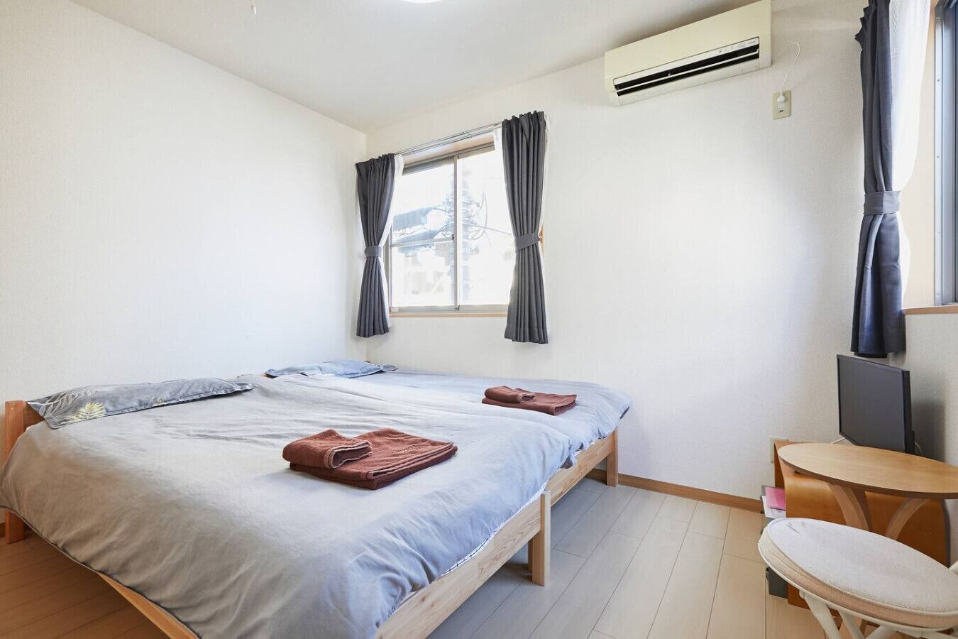 A bedroom with a bed, a desk, and an air conditioning unit.
