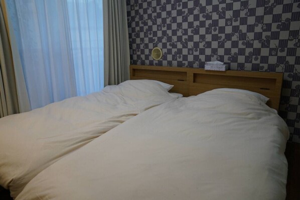 A double bed with white bedding in a room with a checkered wall pattern and a wooden headboard. - Shinjuku 301 for 2 peoples, private toilet + small kitchen (Nakano City)