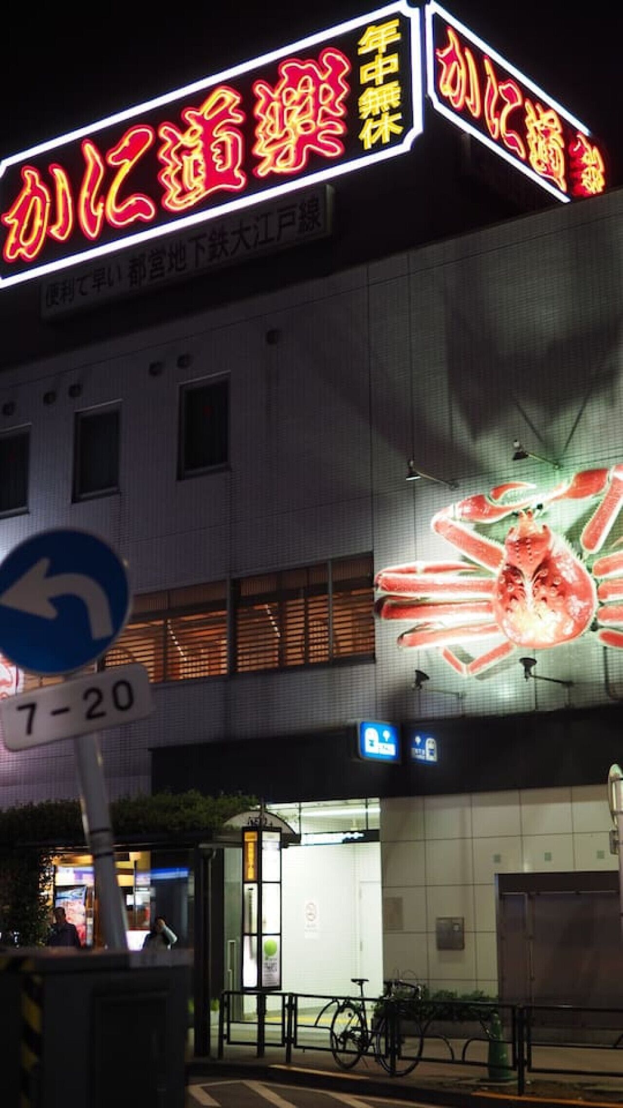 Un edificio con un letrero de neón y una gran imagen iluminada de cangrejo.