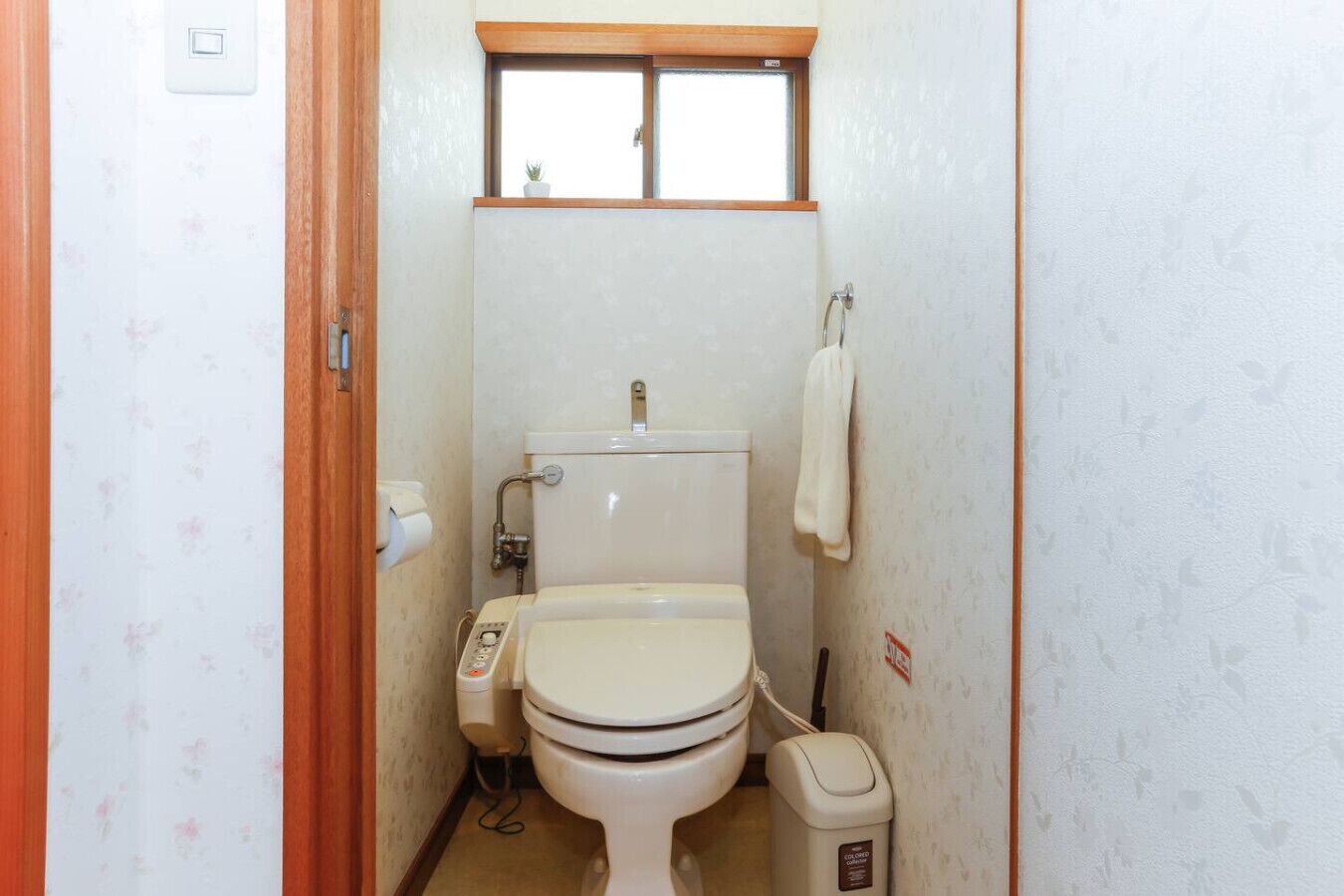 A small, compact bathroom with a toilet, bidet, and a window above the toilet.