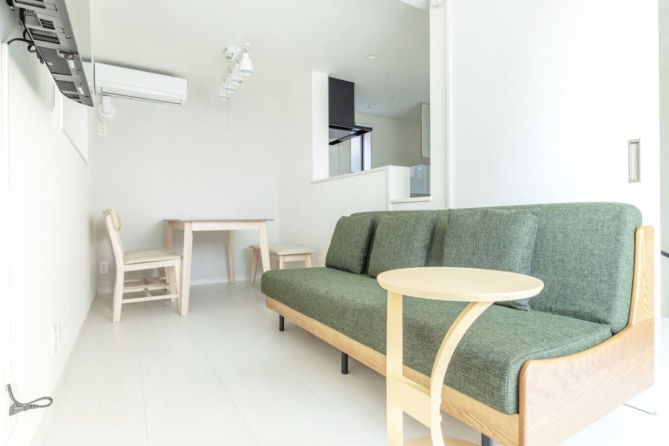 Ein modernes Wohnzimmer mit einem grünen Sofa, einem Holzstuhl, einem kleinen Tisch und einem runden Tisch.