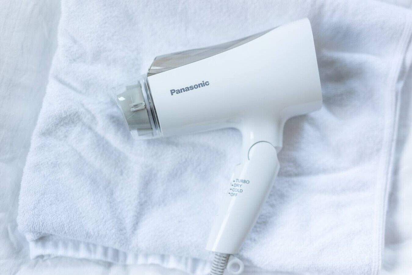 A Panasonic hair dryer with a Turbo, Dry, Cold, and Off setting, placed on a white towel.