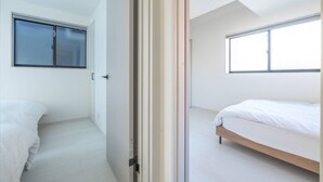 Una habitación con dos camas, una ventana y una puerta.