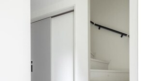 Una escalera moderna y minimalista con paredes blancas y barandilla negra.