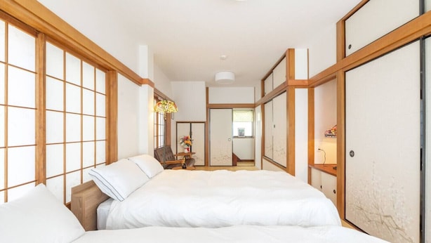 A traditional Japanese-style bedroom with tatami flooring, a low wooden bed frame, and shoji screens. - Kiki`s Delivery Service | Within walking distance of Ikebukuro | A Tokyo home immersed in Studio Ghibli fairy tales (Toshima City)