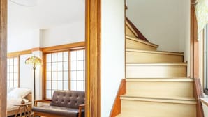 A staircase with wooden steps and a handrail, leading to a room with a sofa and a lamp. - Kiki`s Delivery Service | Within walking distance of Ikebukuro | A Tokyo home immersed in Studio Ghibli fairy tales (Toshima City)