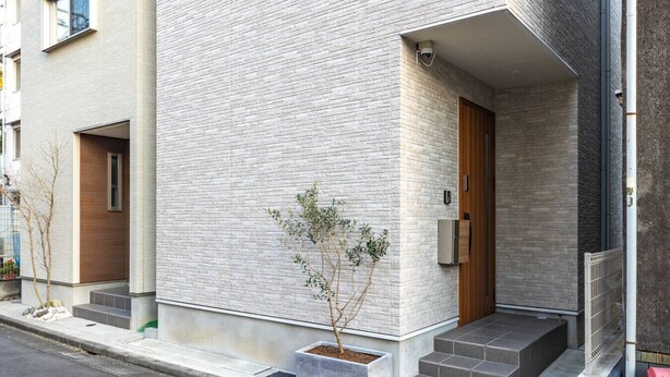 A modern building with a brick facade, a small entrance with steps, and a security camera. - Near Shinjuku 3 stops (Suginami City)