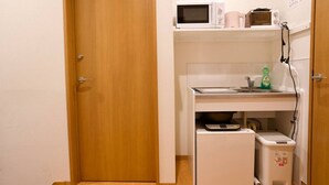 Een kleine keuken met een magnetron, koffiezetapparaat en een vuilnisbakje.