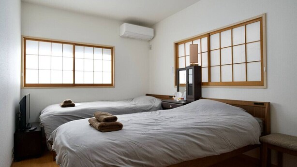 Een hotelkamer met twee bedden, een televisie, een bureau en een kast.