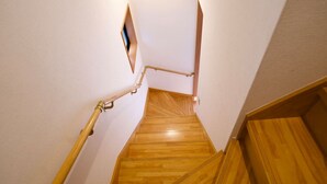 Een houten trap met een leuning, leidend naar een plateau met een klein raam.