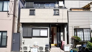 Een woonhuis met twee verdiepingen, een balkon, een garagepoort en een fiets voor de deur.