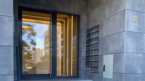 Ingresso di un edificio moderno con porta in vetro, una scalinata in marmo e una cassetta postale a parete.