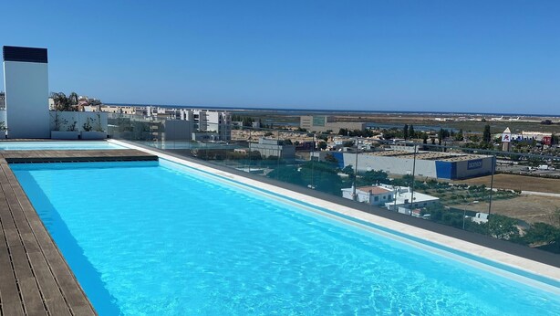 Una piscina a sfioro sul tetto con vista chiara sulla città e sulla costa.