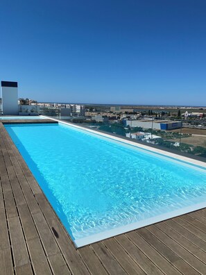 Une piscine à débordement située sur le toit, offrant une vue dégagée sur le paysage urbain et la côte.