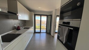 Una cucina moderna con mobili bianchi, un forno Bosch e un bollitore.