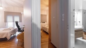A hotel room with a bed, a chair, a desk, and a bathroom with a sink and mirror. - Alopece City Apartment (Athens)