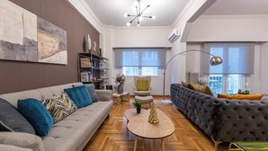 A modern living room with a grey sofa, a dark armchair, and a round coffee table. - Alopece City Apartment (Athens)