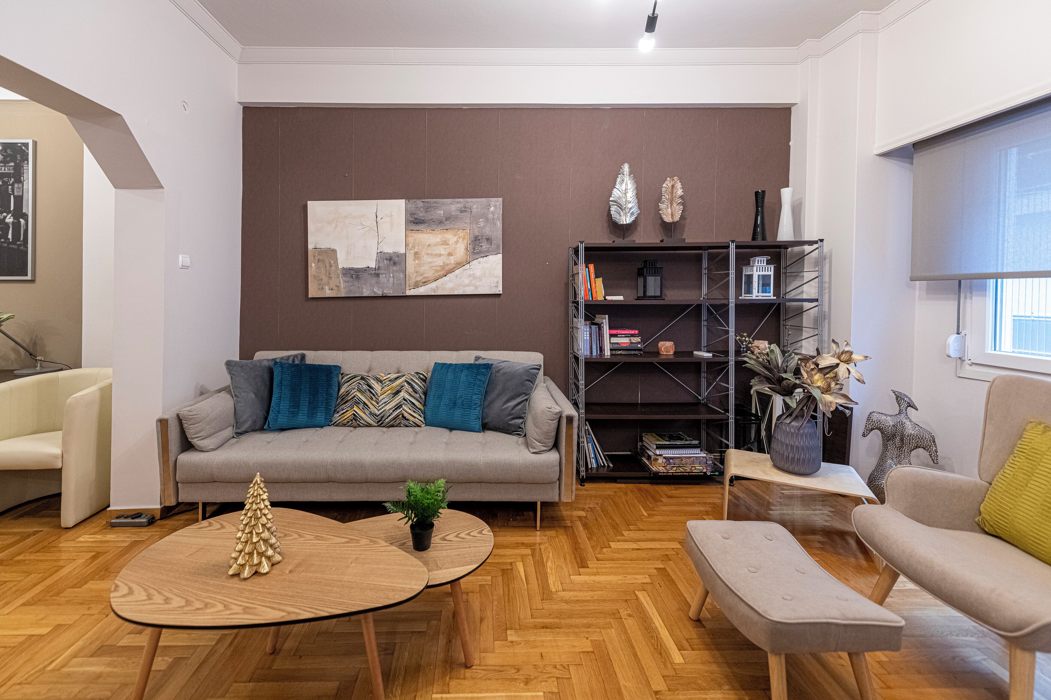 A modern living room with a grey sofa, wooden coffee table, and a bookshelf.