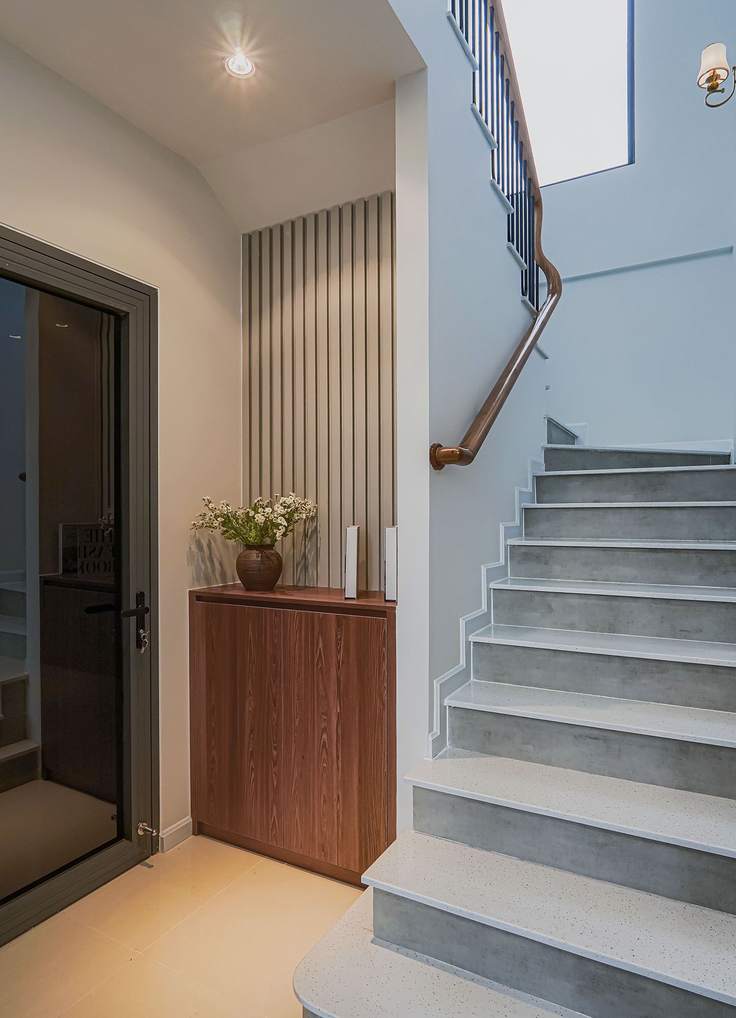 A staircase with a wooden handrail and a wall-mounted light fixture.