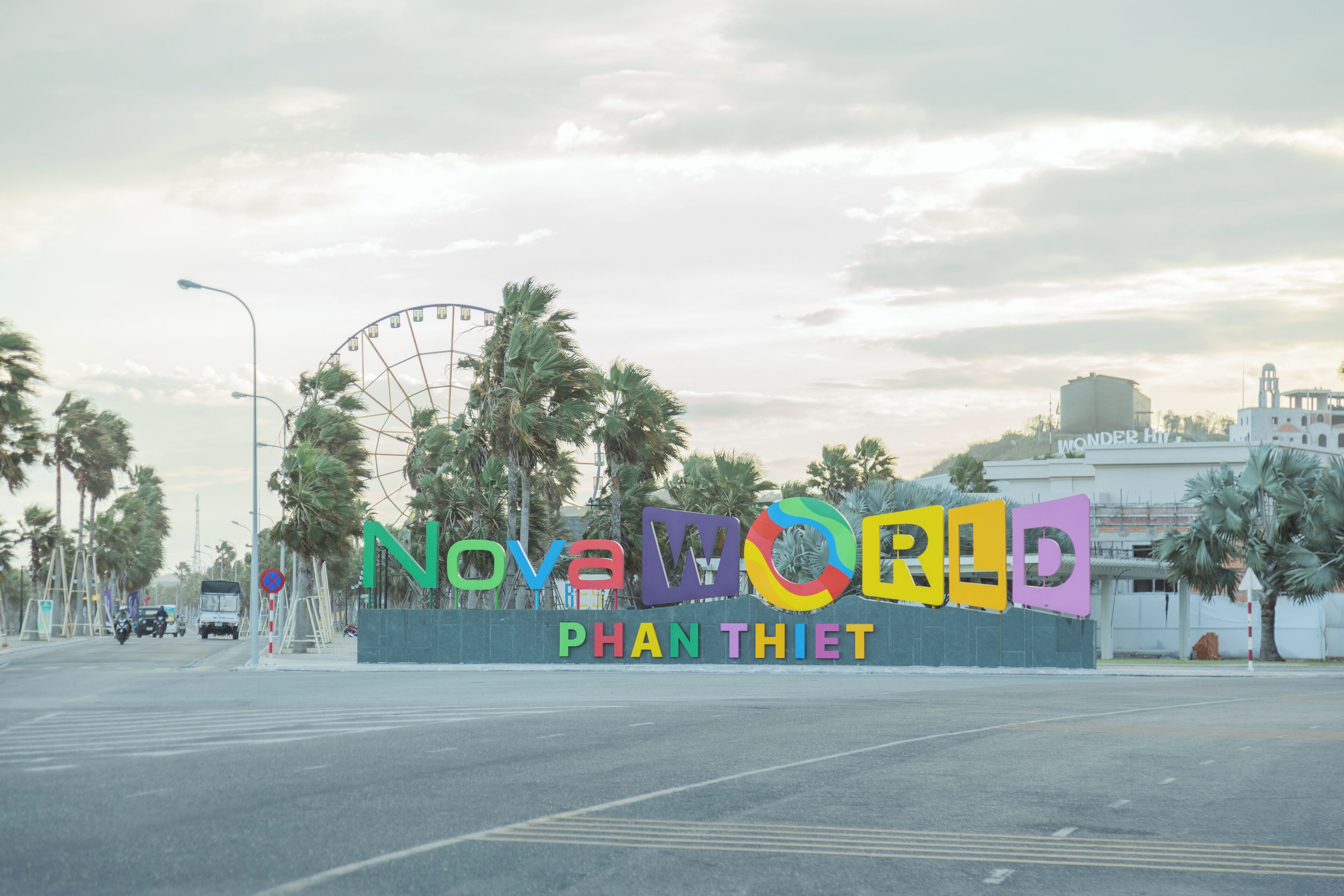 A sign for Nova World Phan Thiet with a Ferris wheel in the background.