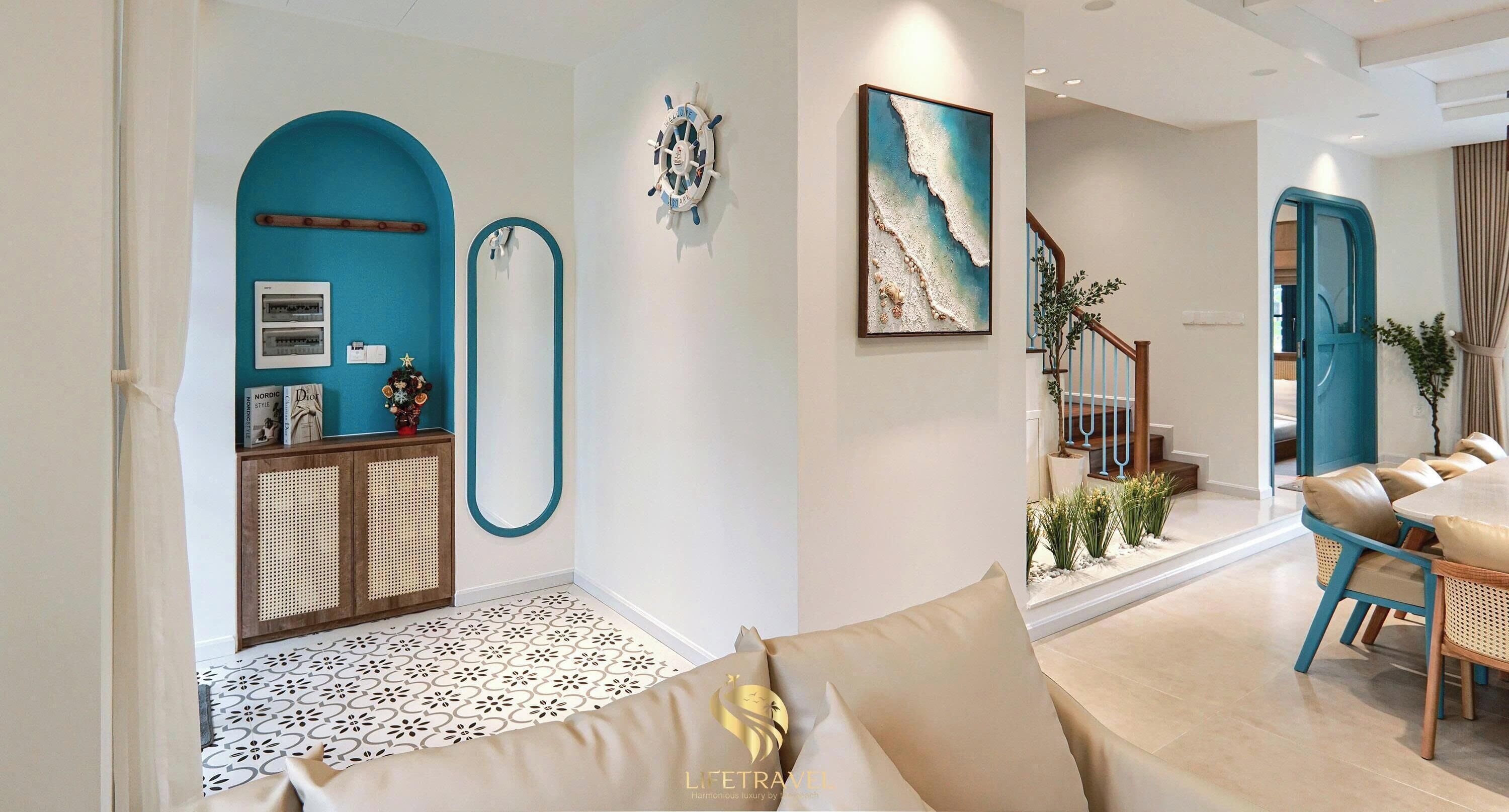 A living room with a sofa, a dining area with a table and chairs, a staircase, and a wall with a nautical-themed decoration.