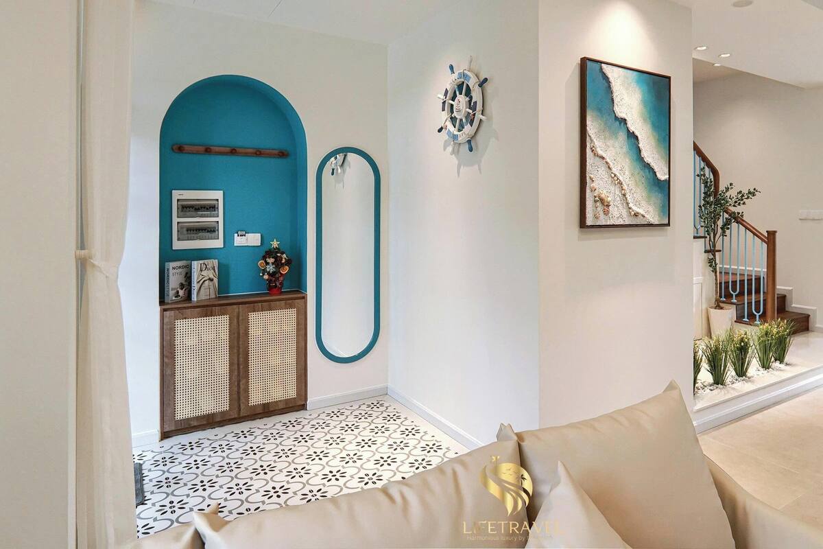 A living room with a sofa, a dining area with a table and chairs, a staircase, and a wall with a nautical-themed decoration.