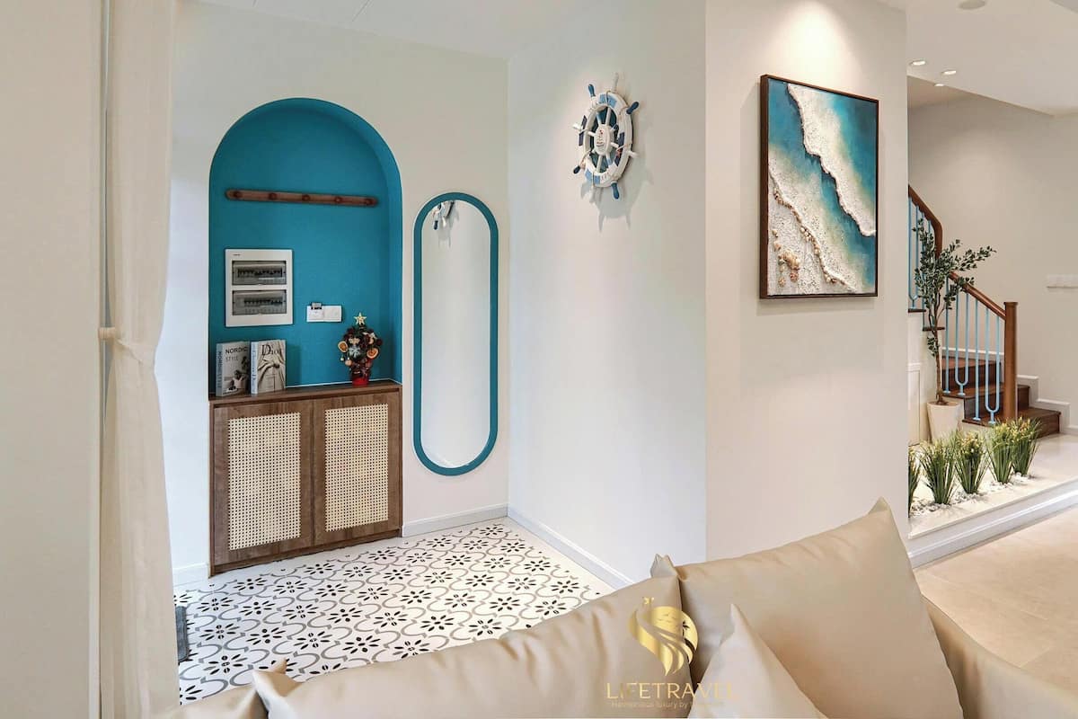 A living room with a sofa, a dining area with a table and chairs, a staircase, and a wall with a nautical-themed decoration.