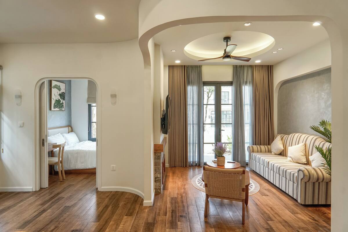 A modern living room with a sofa, a dining table, and a ceiling fan.