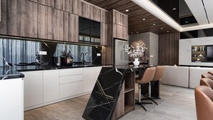 A modern kitchen with a central island, wooden cabinetry, and a built-in oven. - Life Travel Villa - Novaworld Phan Thiet (Tien Thanh)