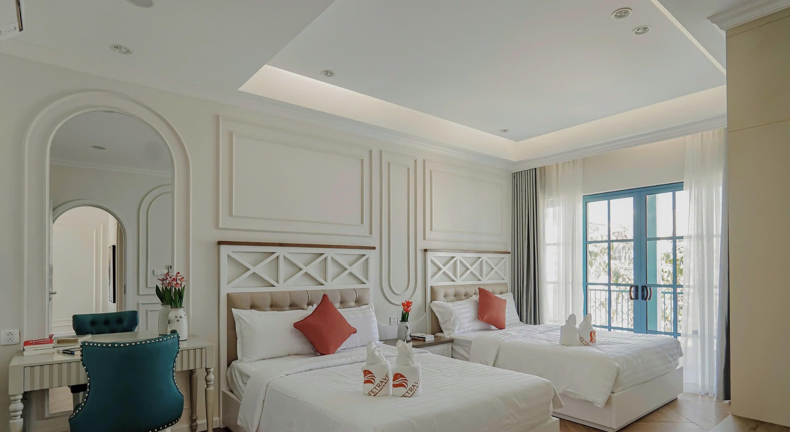 A hotel room with two beds, a desk, a chair, and a large window.