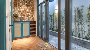 A modern interior with a stone wall, wooden flooring, and a view of bamboo plants outside. - Life Travel Villa - Novaworld Phan Thiet (Tien Thanh)