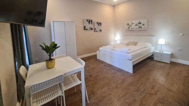 Une chambre à coucher comprenant un lit, un bureau, une chaise, une armoire et des œuvres d’art accrochées aux murs.