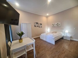 Quarto com cama, escrivaninha, cadeira, guarda-roupa e obras de arte nas paredes.