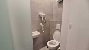 Une salle de bain moderne équipée de toilettes, d’un lavabo et d’une douche.
