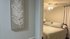 A bedroom with a bed, a nightstand, and a ceiling fan.
