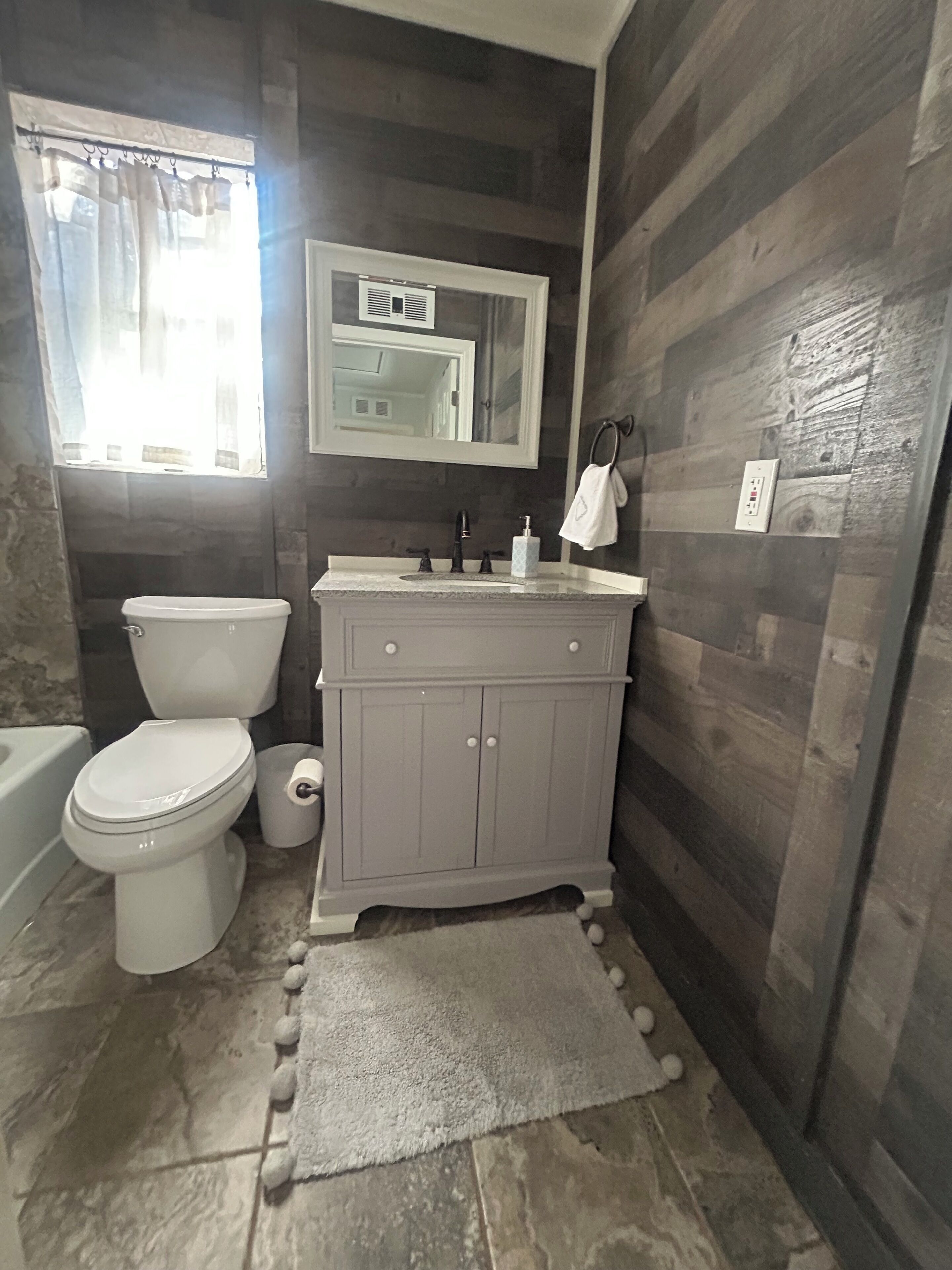A bathroom with a toilet, sink, and mirror.