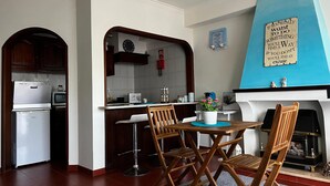 Une cuisine compacte avec un coin repas, comprenant une table en bois, des chaises et un petit réfrigérateur.