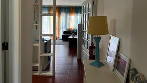Un couloir menant à un salon équipé d’un canapé, d’une lampe et d’un extincteur.