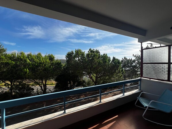 Un balcon donnant sur des arbres et un ciel dégagé.
