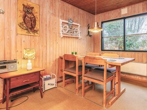 A wooden interior with a dining table, chairs, a lamp, a radio, and a bookshelf. - 4 Person Holiday Home in Hals (Hals)
