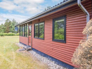 A red wooden building with multiple windows and a door, surrounded by a grassy area and trees. - 4 Person Holiday Home in Hals (Hals)