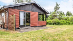 A wooden cabin with a sloped roof, a sliding glass door, and a small porch area. - 4 Person Holiday Home in Hals (Hals)