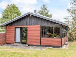 A single-story building with a sloped roof, a large sliding glass door, and a small attached garage.