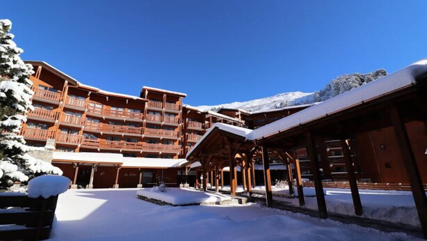 A snow-covered building with multiple balconies and a covered outdoor area. - Apartment in Meribel With Ski-in Access (Les Allues)
