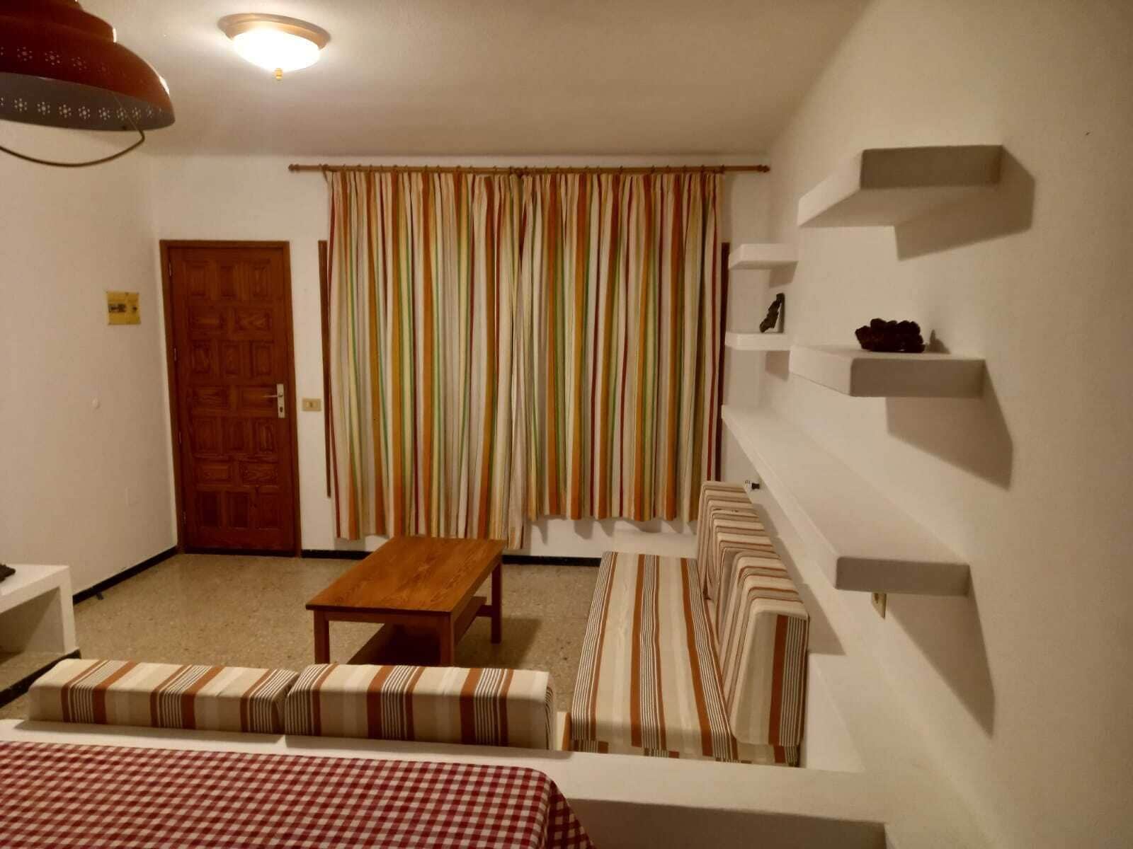 Un petit salon chaleureux, avec une table en bois, un canapé à rayures et un rideau à rayures.