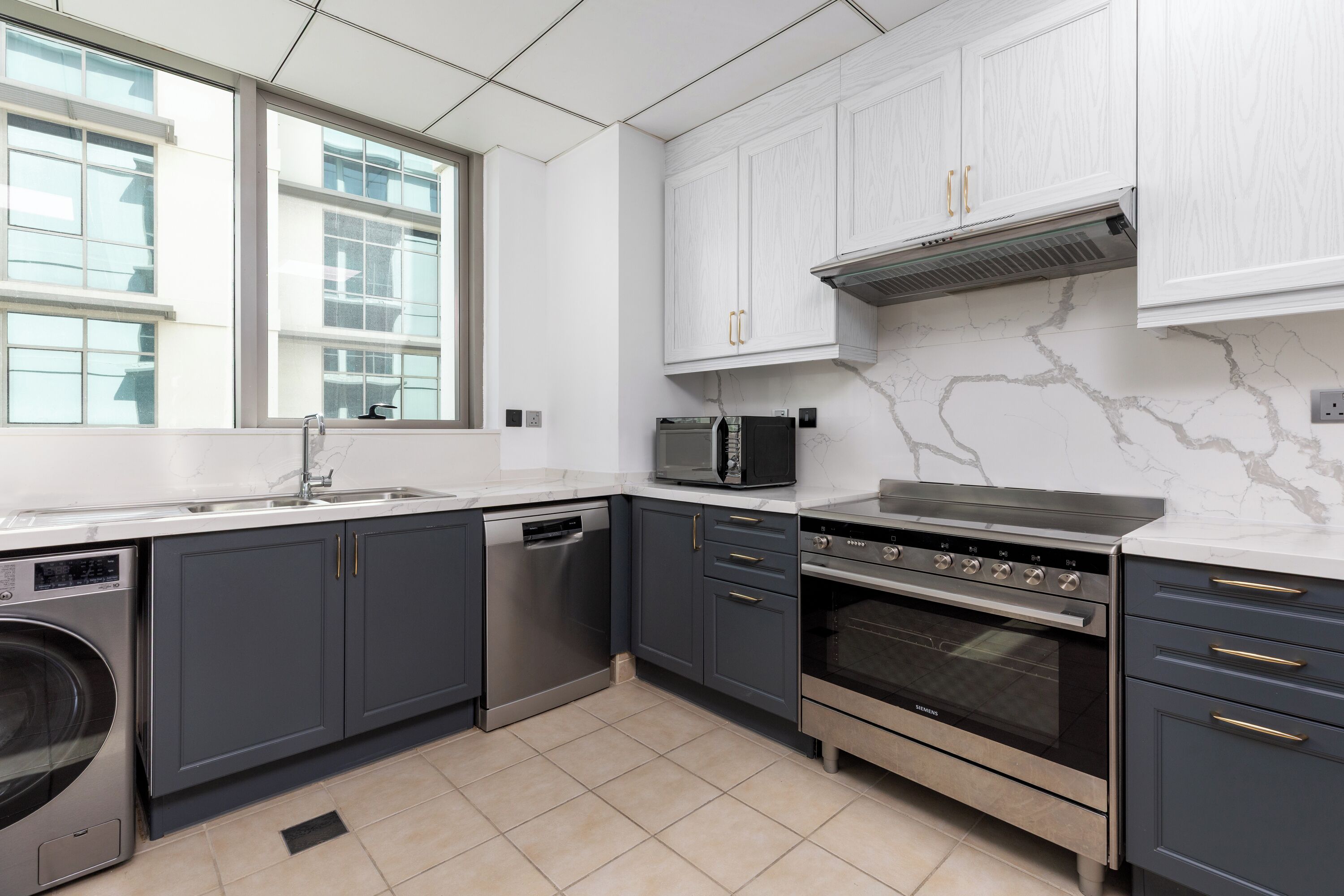 A modern kitchen with grey cabinets, a dishwasher, a microwave, and an oven.