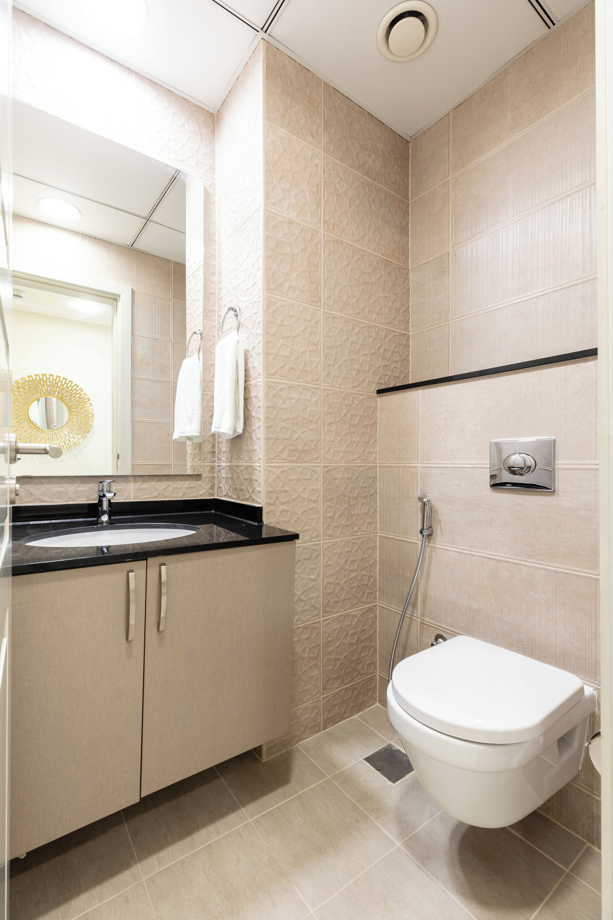 A modern bathroom with a sink, mirror, towel rack, and shower.