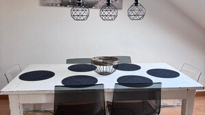 A dining area with a white table, black chairs, and a hanging light fixture above. - In the middle of Lindenthal and with the bus right outside the door to the city center (Köln)