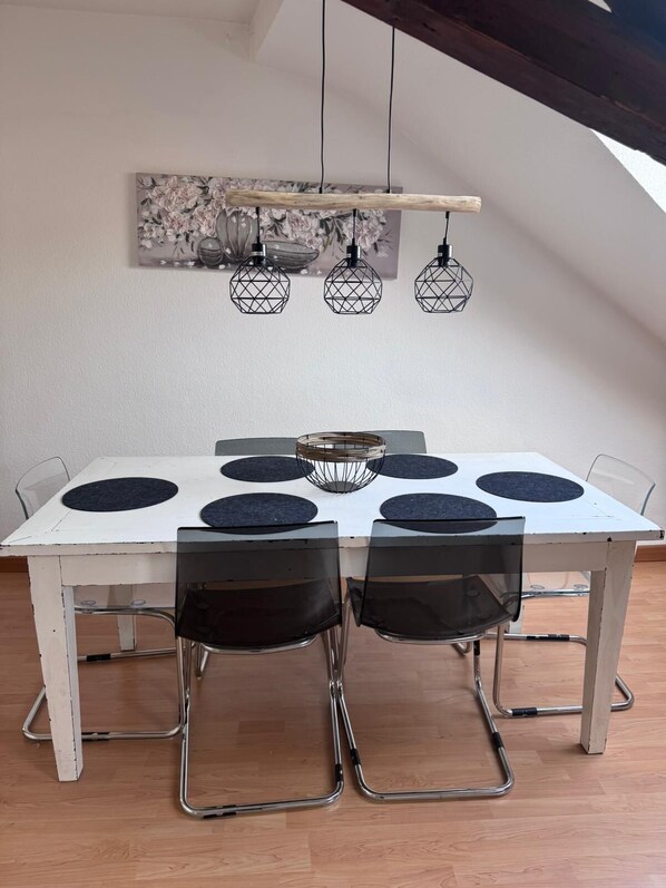 A dining area with a white table, black chairs, and a hanging light fixture above. - In the middle of Lindenthal and with the bus right outside the door to the city center (Köln)