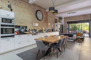 Una cocina moderna con un reloj grande, electrodomésticos integrados y un comedor con sillas y una mesa.